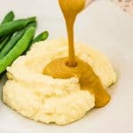 Keto gravy being poured over cauliflower mash.