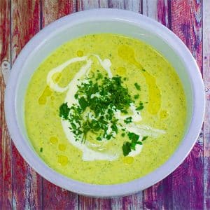 keto broccoli leak soup in a white bowl topped with heavy cream and parsley.