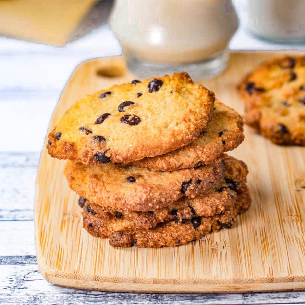 Keto chocolate chip cookies stacked on a wooden serving board.