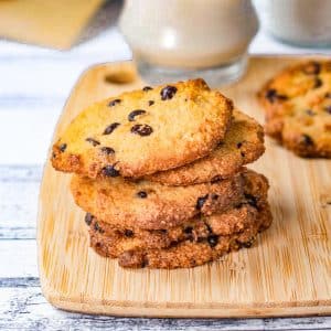 Keto chocolate chip cookies stacked on a wooden serving board.