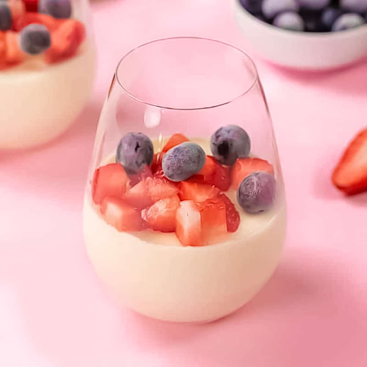 Keto panna cotta in a glass topped with blueberries and strawberries.