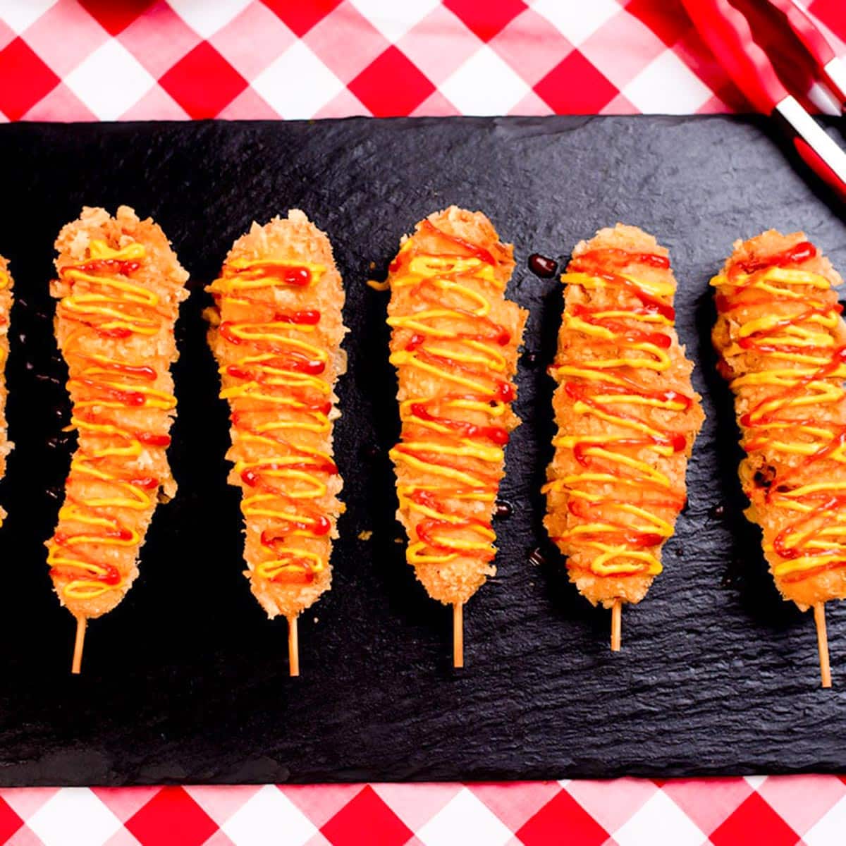 Keto corn dogs on a black serving plater ready for Labor day festivities.